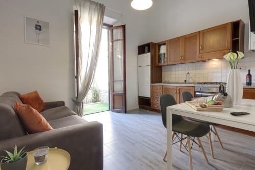 Modern apartment kitchen and living area with wooden cabinets, garden view doors, and comfortable seating at Sleep Tight