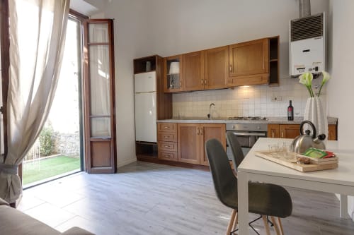 Modern kitchen and dining area in Florence apartment with wood cabinets, garden view through glass door