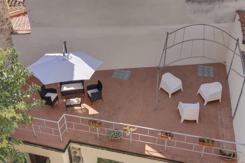 Rooftop terrace at Sleep tight Florence with seating, umbrella, and white lounge chairs overlooking Firenze