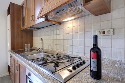 Modern kitchen with gas stove, granite countertop, and white tile backsplash in Florence apartment