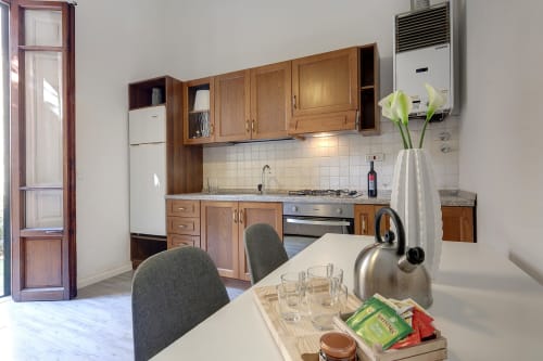 Modern kitchen and dining area in Sleep tight Florence apartment with wooden cabinets, stainless steel appliances, and white