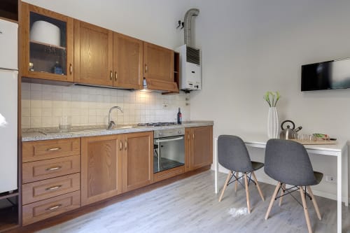 Modern kitchen with wooden cabinets, granite countertop, and dining area with gray chairs at Sleep tight Florence apartment,