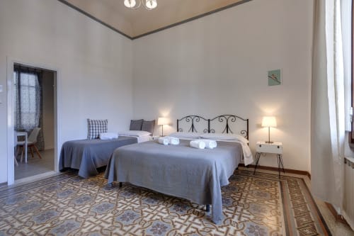 Camera spaziosa al Sleep tight Florence con due letti, testiera in ferro battuto e comodini gemelli a Firenze