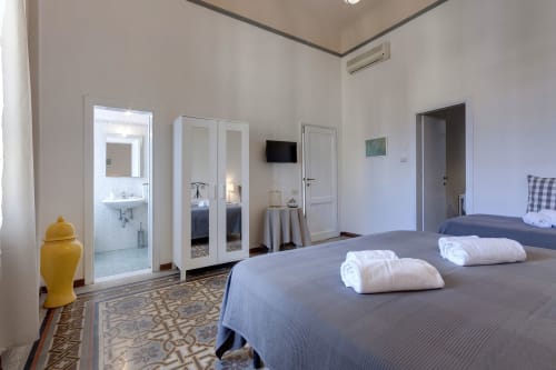 Modern one-bedroom apartment at Sleep tight Florence with two beds, white wardrobe, en-suite bathroom, and yellow decorative