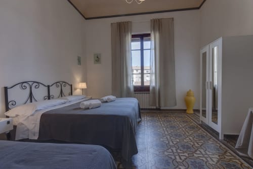 Spacious bedroom in Sleep tight Florence apartment with twin beds, wrought iron headboard, window with city view, and elegant