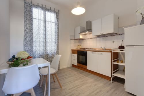 Modern kitchen in Sleep tight Florence one-bedroom apartment with white cabinets, wooden countertops, dining area, and
