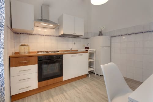 Modern kitchen in Sleep tight Florence one-bedroom apartment with white cabinets, wooden counters, black oven, and stainless
