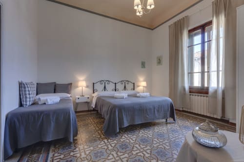 Spacious bedroom at Sleep tight Florence BnB with two beds, elegant decor, and natural light from windows