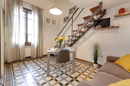 Luminoso loft a Firenze con scale moderne, scrivania, divano e pavimento in piastrelle decorative vicino alla finestra