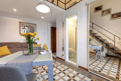 Moderno loft a Firenze con divano marrone, accenti gialli, piastrelle geometriche e bagno ensuite