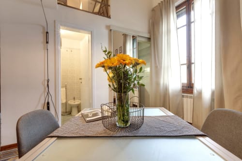 Moderno loft a Firenze con tavolo da pranzo, fiori gialli e luminose finestre sulla città
