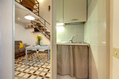 Accogliente monolocale a Firenze con angolo cottura, lavabo e zona living con scala e sedute