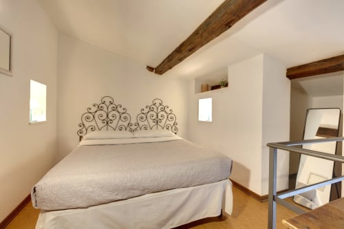 Camera da letto in loft a Firenze con testata in metallo decorato, travi in legno e comfort moderni presso Sleep tight Florence B&B