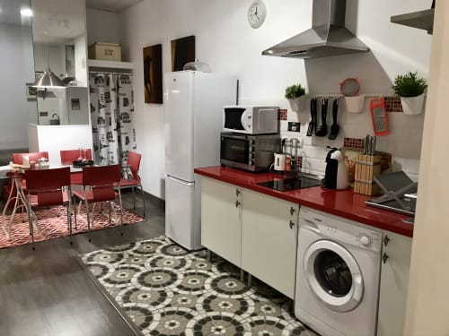 Cocina moderna en Apartamentos Huelintown en Málaga con encimeras rojas, electrodomésticos blancos y zona de comedor