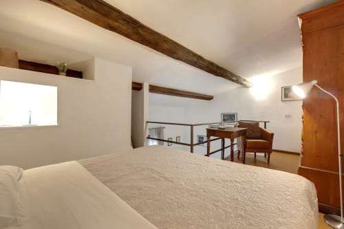 Camera loft moderna a Sleep tight Florence con travi a vista, letto queen, scrivania e zona living in mezzanino a Firenze