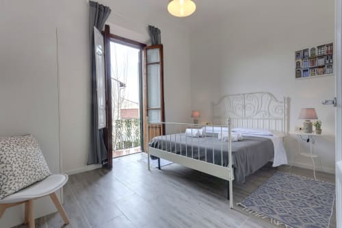Camera moderna a Sleep tight Florence con letto bianco, accesso al balcone e vista sul giardino a Firenze