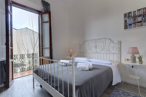Bright bedroom at Sleep tight Florence B&B in Florence with wrought iron bed, garden view balcony, and white nightstands with