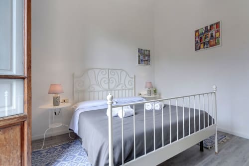 Bright bedroom in Sleep tight Florence B&B with white metal bed frame, bedside lamps, and decorative wall art in Firenze