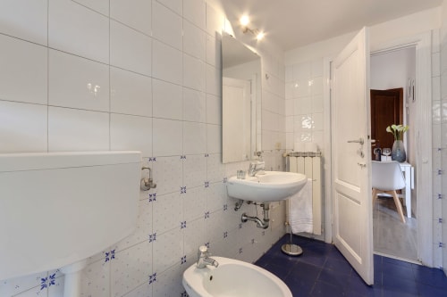 Modern bathroom at Sleep tight Florence with white tiles, blue accents, dual sinks, and dark flooring in Garden view