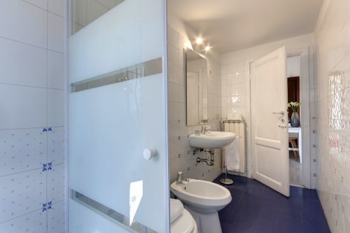 Modern bathroom in Sleep tight Florence garden view apartment with shower, sink, bidet, and white tiled walls
