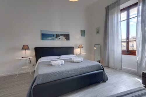Modern bedroom at Sleep tight Florence with black bed, garden view balcony, bedside lamps, and minimalist decor in Florence