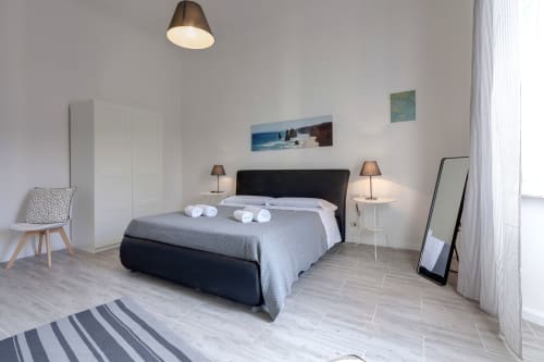 Modern bedroom at Sleep Tight Florence with black bed, white wardrobe, twin bedside lamps, and garden view artwork in Firenze