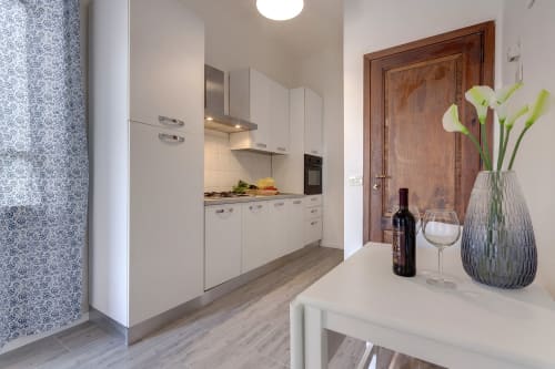 Modern white kitchen with stove, white wine glass, red wine bottle, and green calla lilies at Sleep Tight Florence garden
