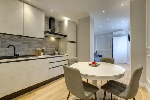 Modern kitchen and dining area in Sleep tight Florence suite, featuring white cabinetry, gray backtile, round white table