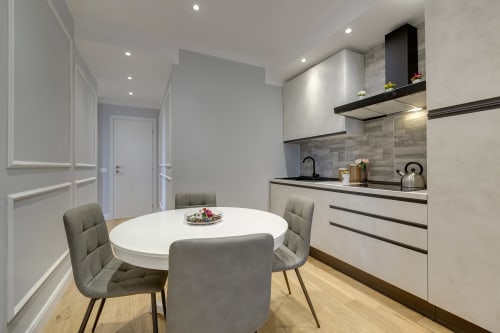 Modern dining area in Sleep tight Florence suite with round white table, gray chairs, and equipped kitchen with black