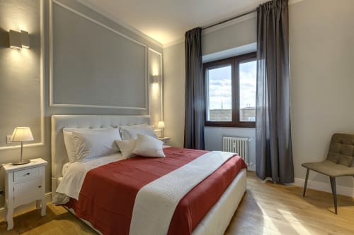 Modern bedroom suite at Sleep tight Florence with red and white bedding, city view from balcony, and contemporary furnishings