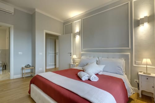Modern suite bedroom at Sleep tight Florence with red and white bedding, city view, neutral decor, and contemporary lighting