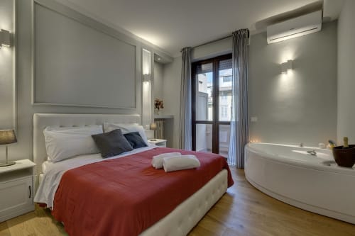 Suite di lusso a Sleep tight Florence con coperta rossa, biancheria bianca, vasca idromassaggio in camera, accesso al balcone e