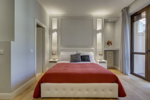 Camera moderna a Sleep tight Florence con coperta rossa, letto bianco e accesso al balcone nella suite dell'appartamento di Firenze