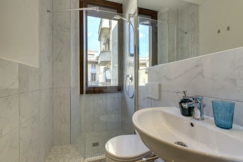 Lussuoso bagno in marmo con doccia open space, lavabo rotondo e finestra vista Firenze nella suite Sleep Tight BnB