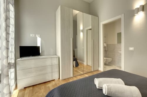 Camera moderna presso Sleep tight Florence con armadio in legno chiaro, TV su cassettone e bagno ensuite con doccia, Firenze