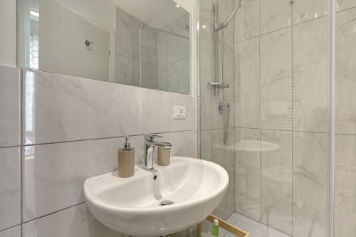 Modern bathroom with double sink, marble tiles, and glass shower enclosure at Sleep tight Florence bed and breakfast in