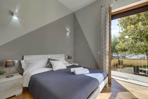 Modern bedroom at Sleep tight Florence with garden view, queen bed, white bedside table, and sliding doors opening to terrace