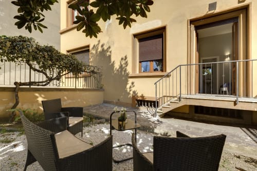 Florence B&B private garden seating area with patio chairs, cream building facade, and glass doors to guest room
