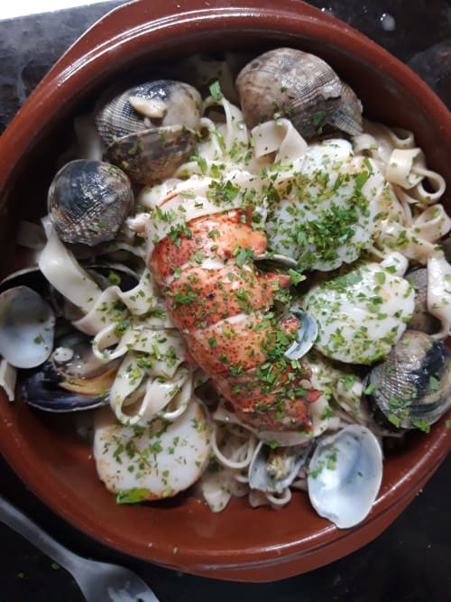 Mariscada con almejas, vieira y hierbas frescas en cuenco de barro en El Paraje del Chef, Granada