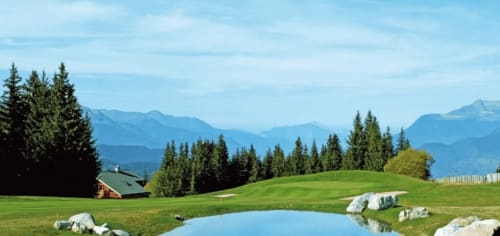 Prairie alpine avec étang à CMD Méribel Le Pralin aux Allues, montagnes et forêt en arrière-plan