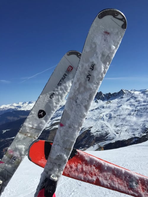 Skis enneigés à la station de ski de Méribel avec les Alpes et les pistes en arrière-plan