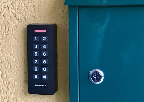 Teclado Fermax y cerradura en puerta turquesa de entrada a Apartamentos Huelintown, hotel en Málaga
