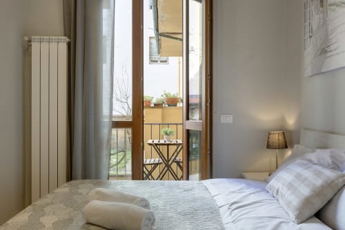 Camera luminosa al Sleep Tight Florence B&B con accesso al balcone, biancheria bianca, termosifone e vista sul giardino privato