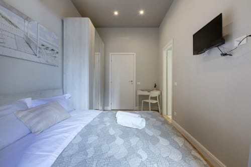 Camera moderna al Sleep tight Florence B&B a Firenze con letto, TV a schermo piatto, scrivania e accesso balcone con vista giardino