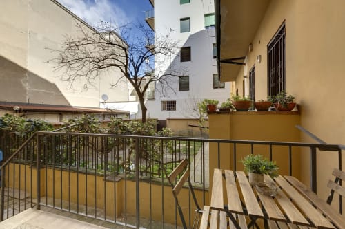 Balcone luminoso con mobili in legno e piante in vaso con vista sul giardino del Sleep tight Florence B&B a Firenze