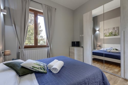 Sleep tight Florence standard room with blue bedding, mirror wardrobe, and window in Firenze