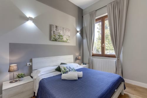 Modern bedroom at Sleep Tight Florence with blue bedding, wooden bed frame, and bright natural light from window