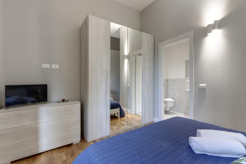 Modern bedroom at Sleep tight Florence with blue bed, mirrored wardrobe, flat-screen TV, and ensuite bathroom