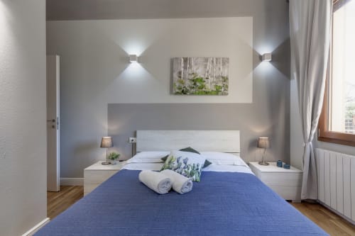 Modern bedroom at Sleep tight Florence B&B with blue bedding, white headboard, wall sconces, and artwork