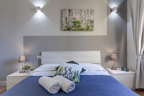Modern bedroom at Sleep tight Florence with blue bedding, white pillows, two rolled towels, birch forest artwork, and